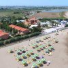 Spiaggia con ombrelloni verdi e area residenziale sullo sfondo.